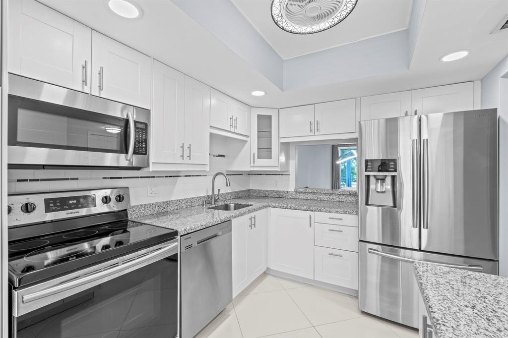 3090 North Course Drive, Unit 309 Pompano Beach, FL 33069 - Photo 7 of 21 a kitchen with stainless steel appliances a refrigerator stove microwave and sink