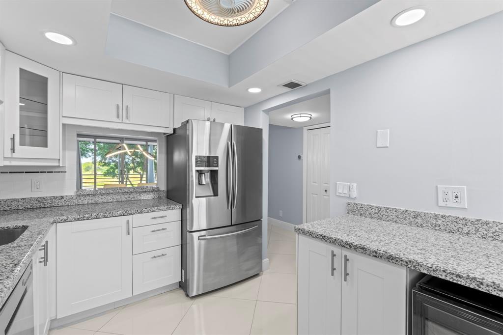 3090 North Course Drive, Unit 309 Pompano Beach, FL 33069 - Photo 8 of 21 a kitchen with granite countertop stainless steel appliances a refrigerator sink and microwave