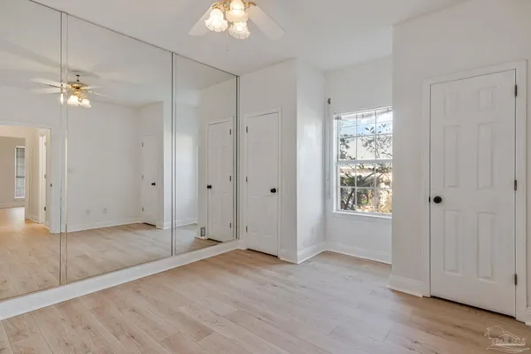 an empty room with wooden floor chandelier fan and windows
