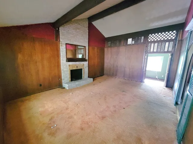 en empty room with windows and fireplace