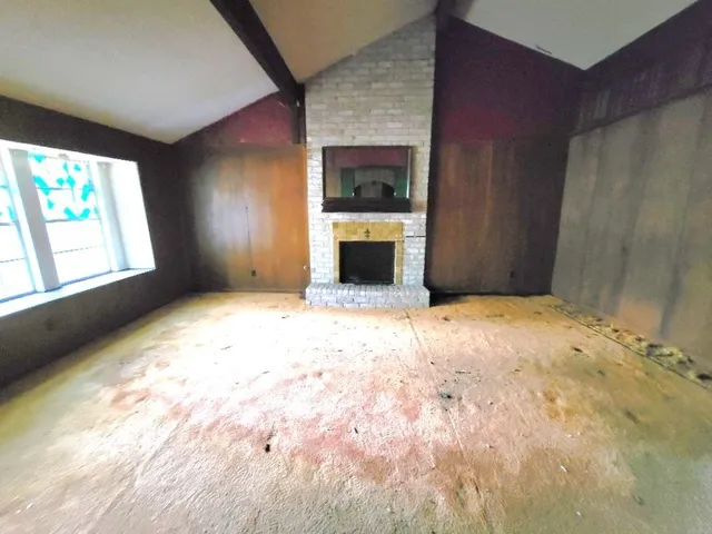 a view of an empty room with a fireplace and a window