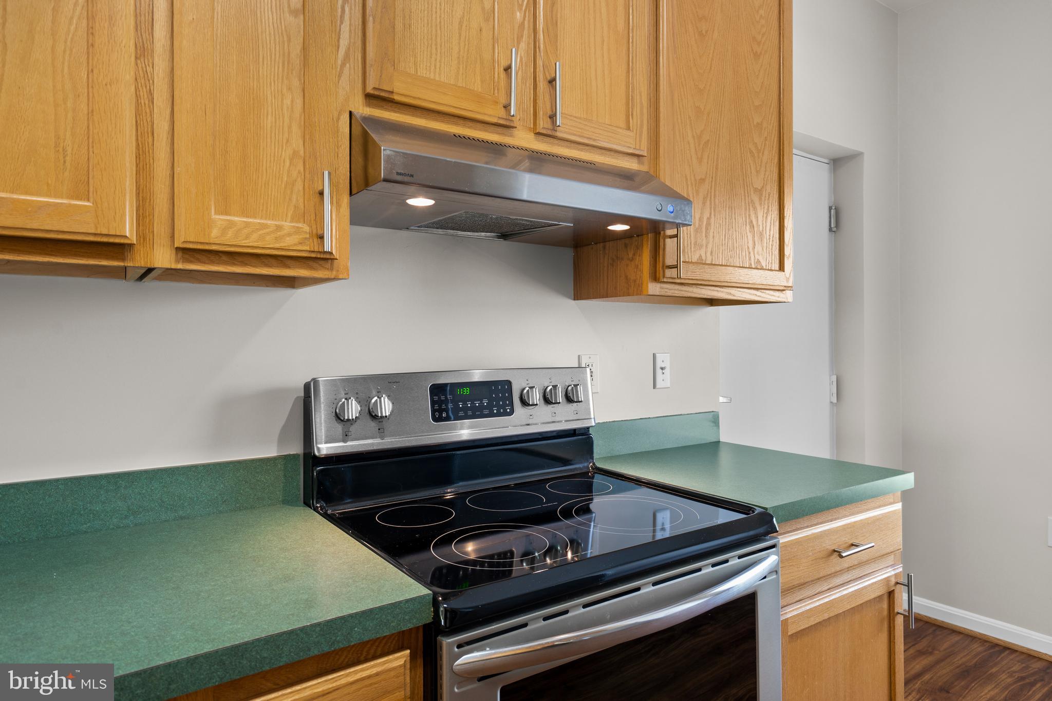 402 Main Street, Unit 300 Gaithersburg, MD 20878 - Photo 11 of 30 a kitchen with wooden cabinets and a stove top oven