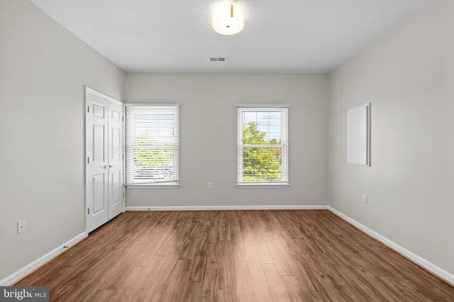 an empty room with wooden floor and windows