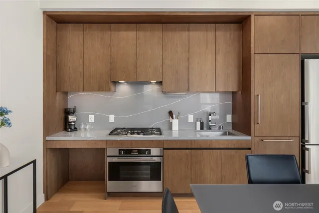 a kitchen with stainless steel appliances granite countertop a refrigerator a stove and a sink with wooden cabinets