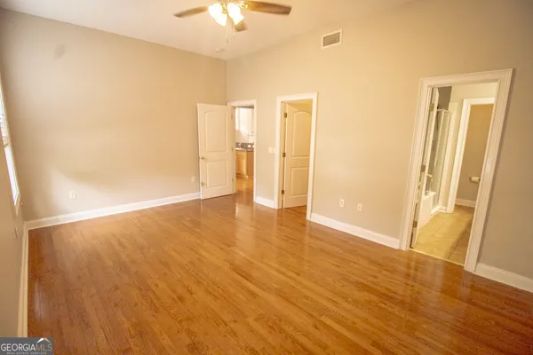 an empty room with wooden floor and chandelier fan