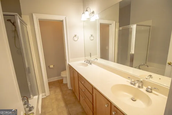 a spacious bathroom with a double vanity sink a mirror and a shower