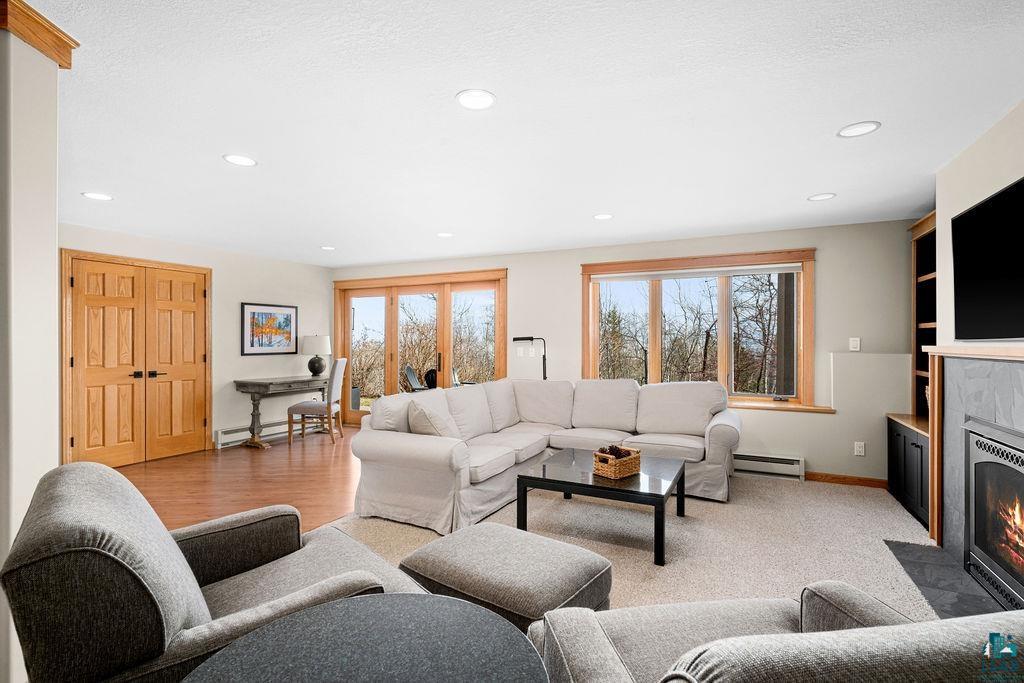 4856 Kingston Street Duluth, MN 55804 - Photo 48 of 88 Spacious living area featuring recessed lighting, a built-in fireplace with a stone surround, wood-finish flooring, and large windows with natural wood trim