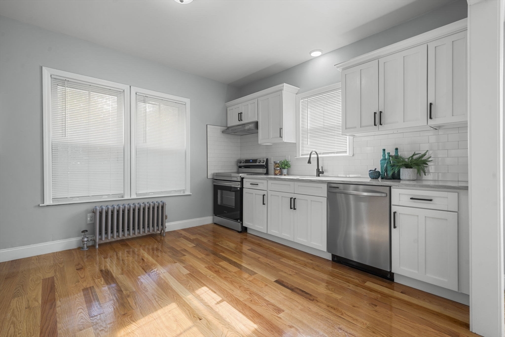 71 School Street, Unit 71 Acton, MA 01720 - Photo 8 of 38 a kitchen with white cabinets a sink dishwasher and a stove with wooden floor