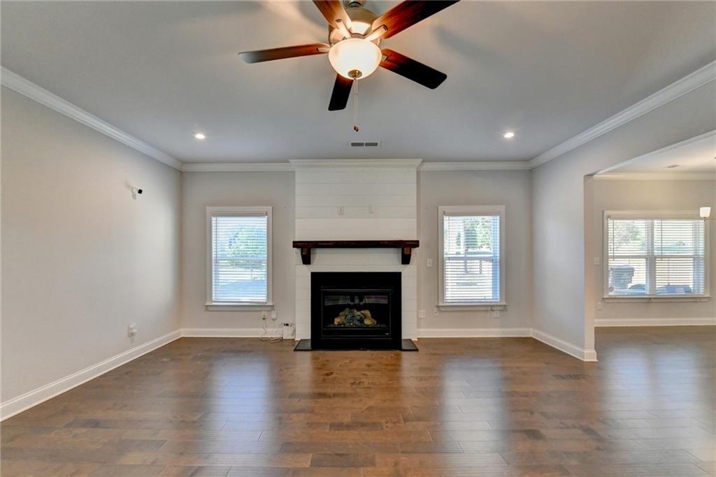 4548 Red Blossom Trail Southwest Powder Springs, GA 30127 - Photo 16 of 72 an empty room with windows a fireplace a ceiling fan and wooden floor