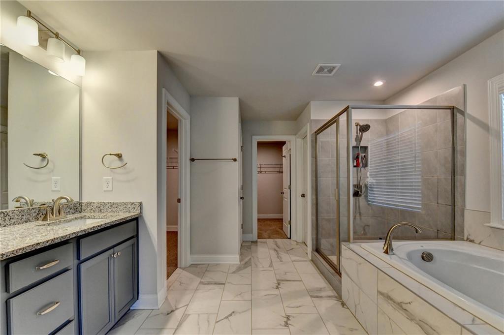 4548 Red Blossom Trail Southwest Powder Springs, GA 30127 - Photo 58 of 72 a bathroom with a granite countertop sink a mirror a bathtub and shower
