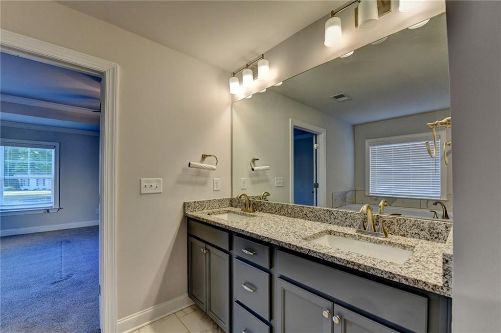 4548 Red Blossom Trail Southwest Powder Springs, GA 30127 - Photo 64 of 72 a bathroom with a granite countertop sink and a mirror