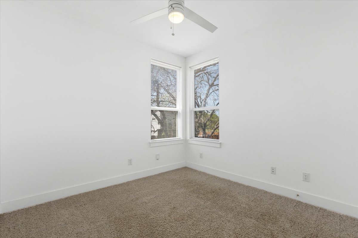 1114 Walton Lane, Unit A Austin, TX 78721 - Photo 15 of 36 Carpeted empty room featuring baseboards and ceiling fan