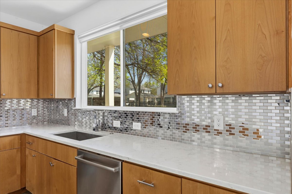 1114 Walton Lane, Unit A Austin, TX 78721 - Photo 8 of 36 Kitchen with dishwasher, light stone countertops, tasteful backsplash, and wood finish cabinetry