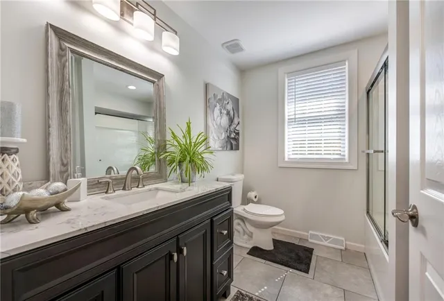 a bathroom with a granite countertop sink toilet a large mirror and a window
