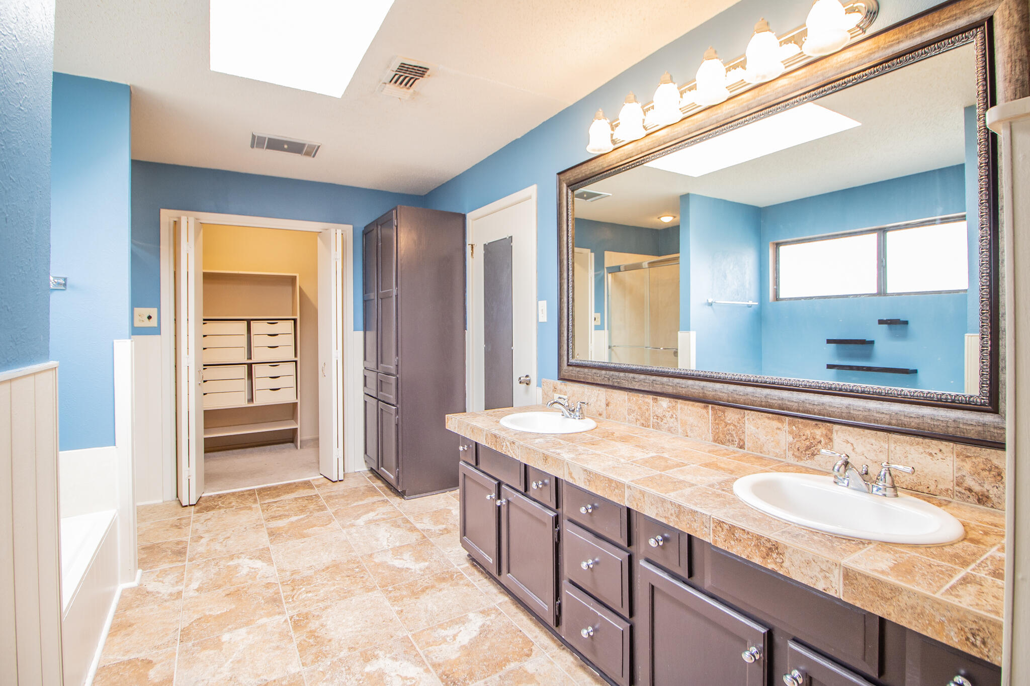 2806 58th Street Lubbock, TX 79413 - Photo 22 of 35 a bathroom with a sink double vanity granite tub shower and a mirror