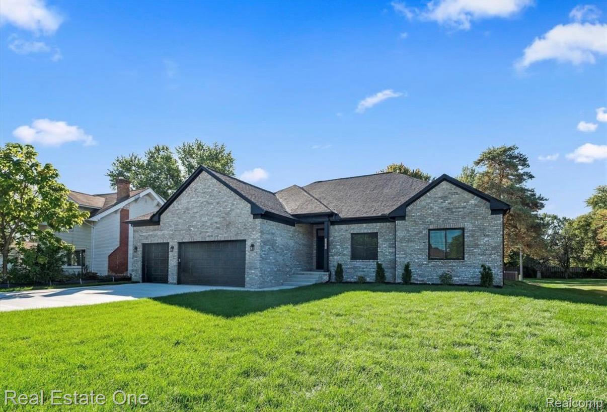 5636 Paris Street Sterling Heights, MI 48310 - Photo 3 of 37 View of front facade with a front lawn, an attached garage, concrete driveway, and brick siding