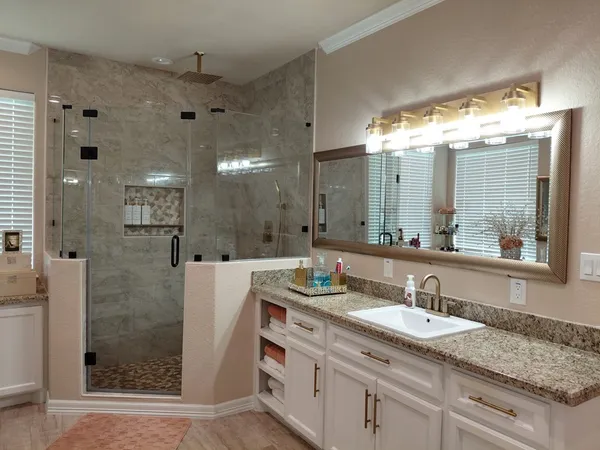 a bathroom with a granite countertop sink shower and a mirror