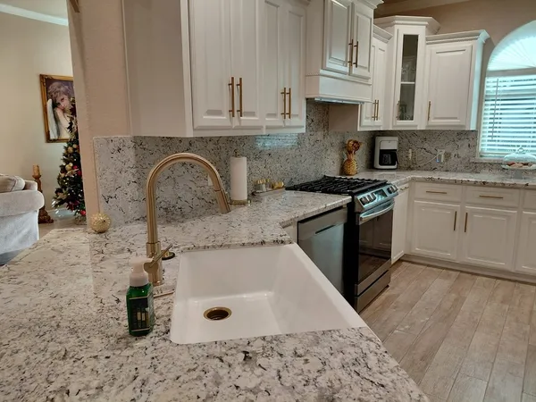 a kitchen with granite countertop a sink a stove and cabinets