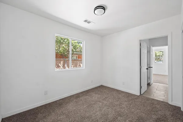 an empty room with a window and a fan
