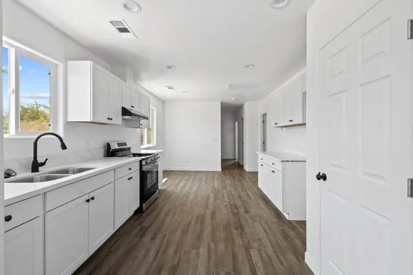 a view of a kitchen with kitchen island a sink wooden floor and stainless steel appliances
