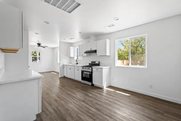 a kitchen with granite countertop a stove a sink dishwasher and a refrigerator with wooden floor