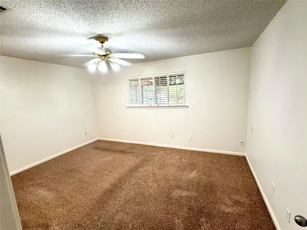 an empty room with a chandelier fan and windows