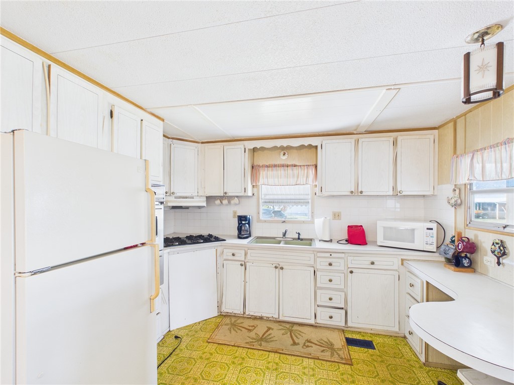 6135 98th Lane Sebastian, FL 32958 - Photo 6 of 18 a kitchen with a sink refrigerator and cabinets