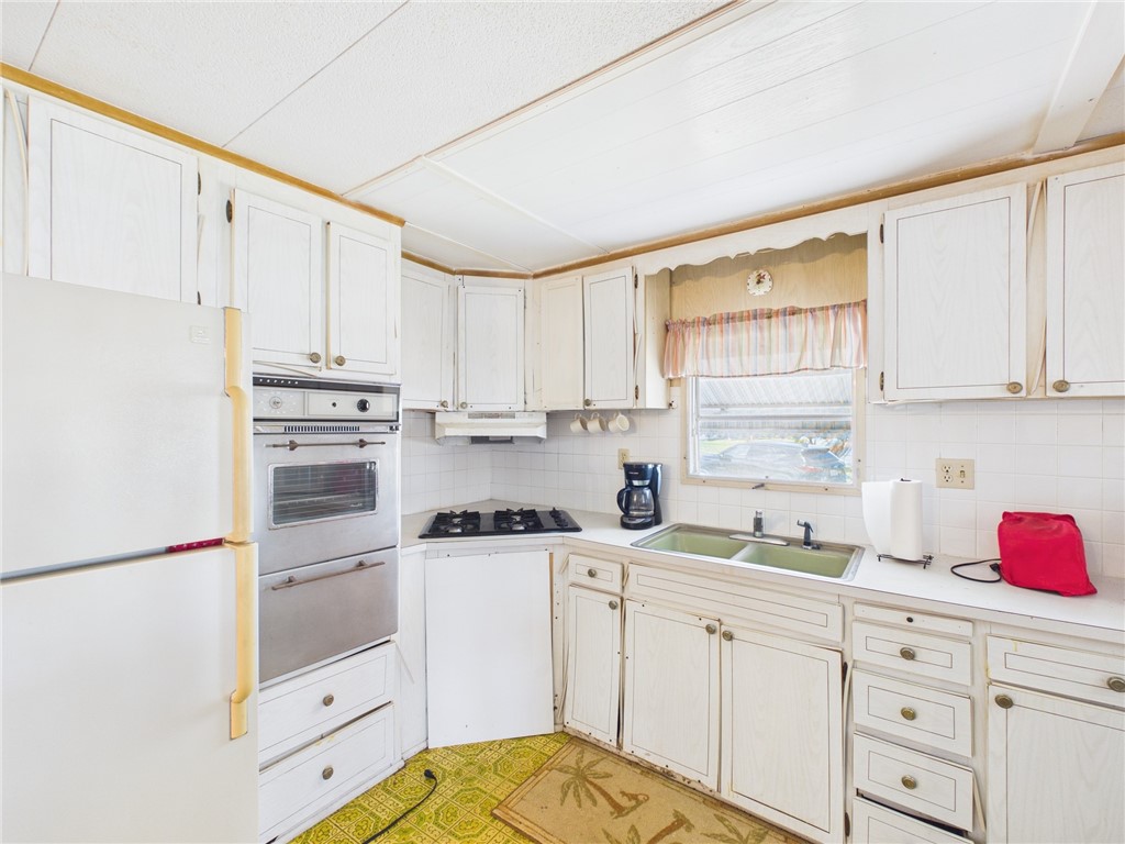 6135 98th Lane Sebastian, FL 32958 - Photo 7 of 18 a kitchen with white cabinets sink and white appliances