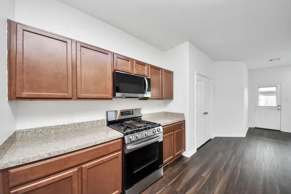 a kitchen with granite countertop a stove a sink and wooden floor