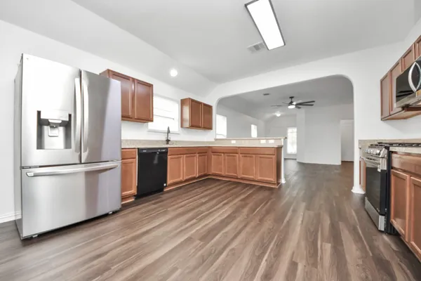 a kitchen with stainless steel appliances a stove top oven a sink dishwasher and a refrigerator