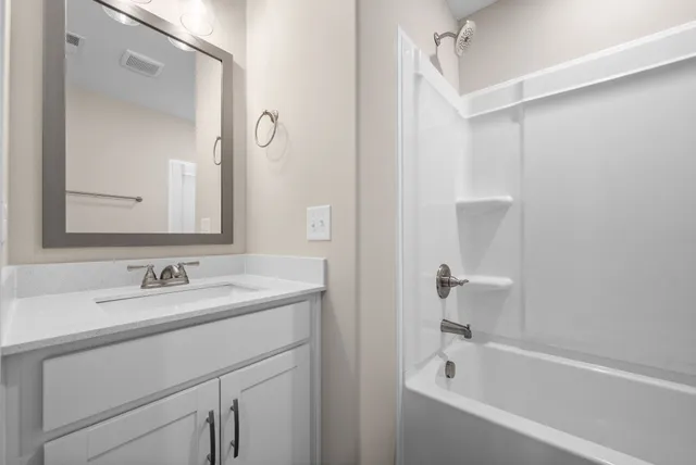 a white bath tub sitting next to a white sink and vanity