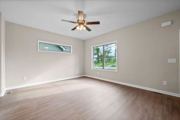 a view of room with window ceiling fan and hardwood floor