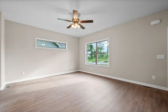 a view of room with window ceiling fan and hardwood floor