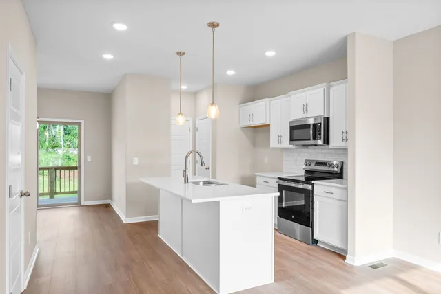 a kitchen with stainless steel appliances kitchen island a sink stove and cabinets