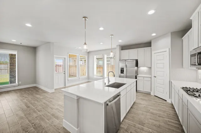 a kitchen with stainless steel appliances kitchen island a large counter top and a wooden floors