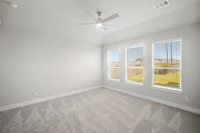 an empty room with windows and ceiling fan