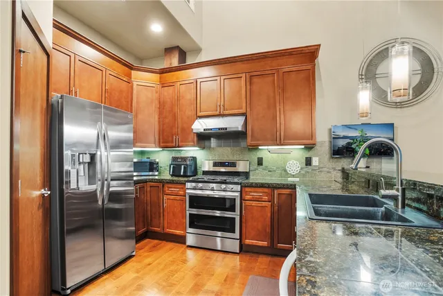 a kitchen with stainless steel appliances granite countertop a stove refrigerator and cabinets