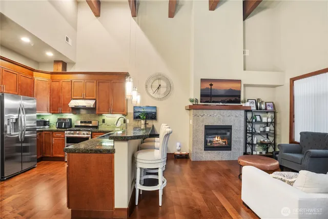 a kitchen with stainless steel appliances granite countertop a stove top oven a sink dishwasher a dining table and chairs with wooden floor