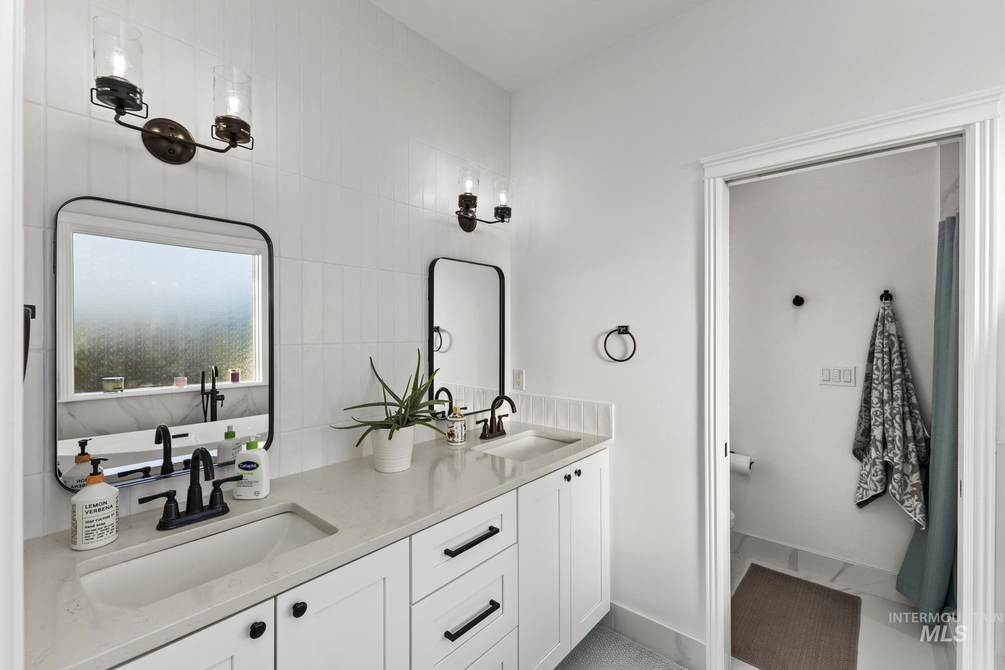 14820 Worden Way Caldwell, ID 83607 - Photo 24 of 44 Bathroom with double vanity, light tile patterned floors, and tile walls