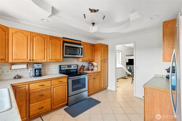 a kitchen with stainless steel appliances granite countertop a stove top oven a sink dishwasher a dining table and chairs with wooden floor