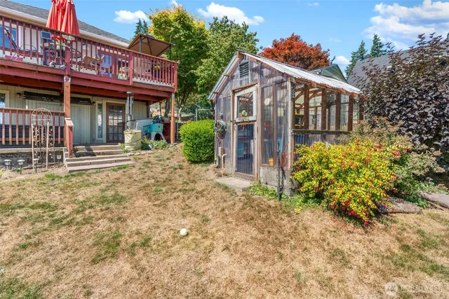 a view of a house with brick walls plants and large tree