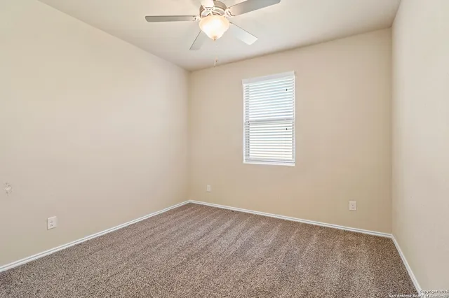 an empty room with a window and a ceiling fan