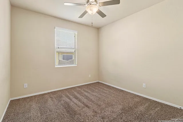 an empty room with a chandelier fan and windows
