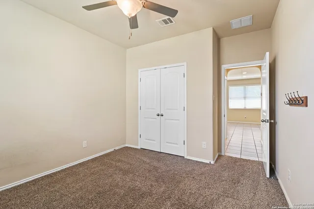 an empty room with closet and a chandelier fan