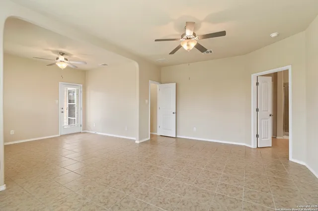 a view of an empty room with a chandelier fan