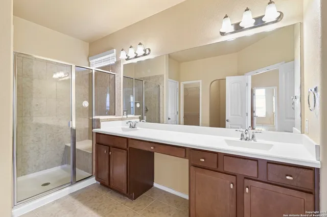 a bathroom with a double vanity sink mirror and shower