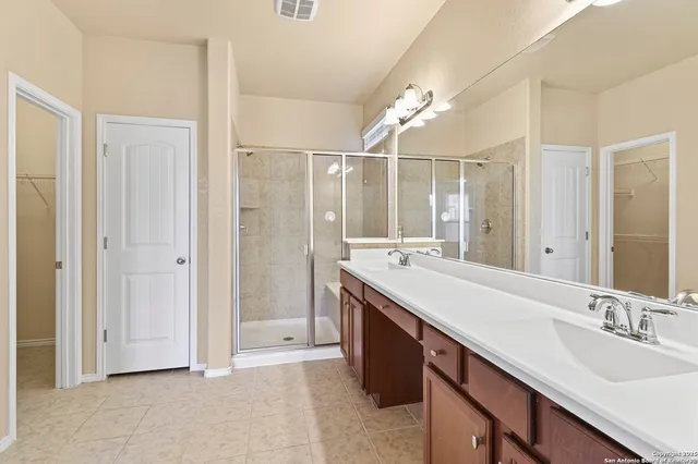 a bathroom with a double vanity sink mirror and shower