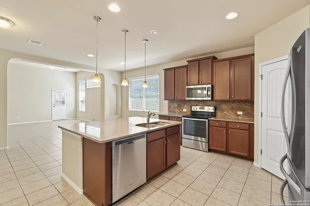 a kitchen with stainless steel appliances granite countertop a refrigerator and a stove top oven