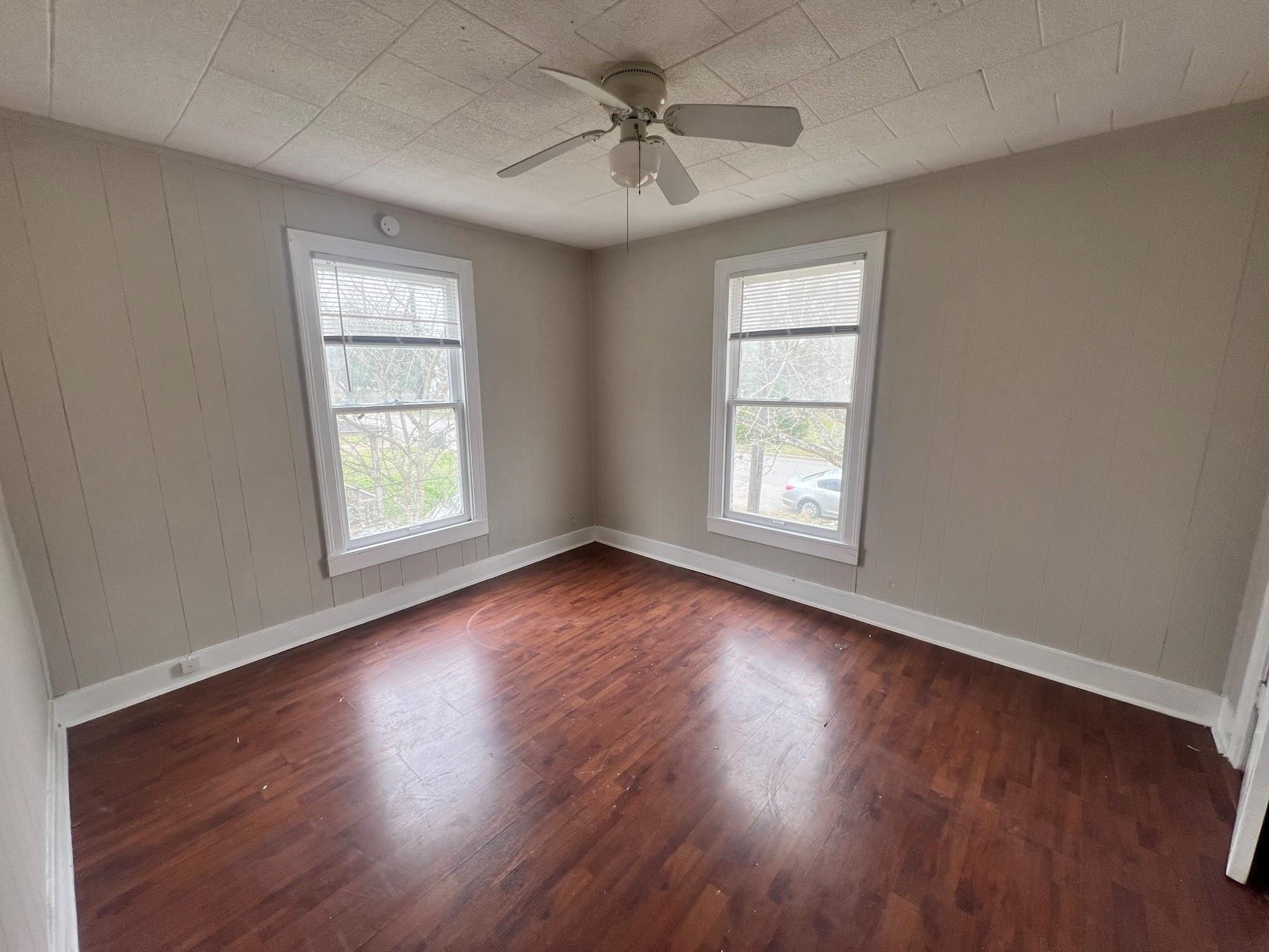 312 South Pumphrey Street Edna, TX 77957 - Photo 3 of 12 an empty room with wooden floor chandelier fan and windows