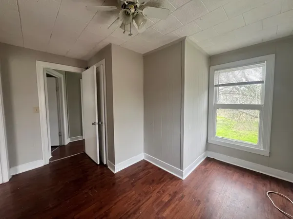 an empty room with wooden floor closet and windows